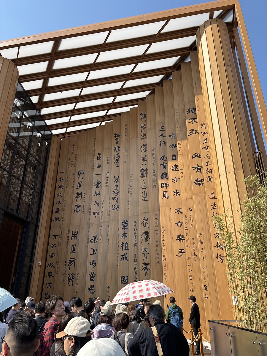 この写真は、大阪・関西万博2025（EXPO 2025）に出展している中国館の入り口だと思われます。

壁に大きく書かれているのは、中国の古典文学、特に「論語」や「詩経」などの中から選ばれた有名な言葉や詩文です。