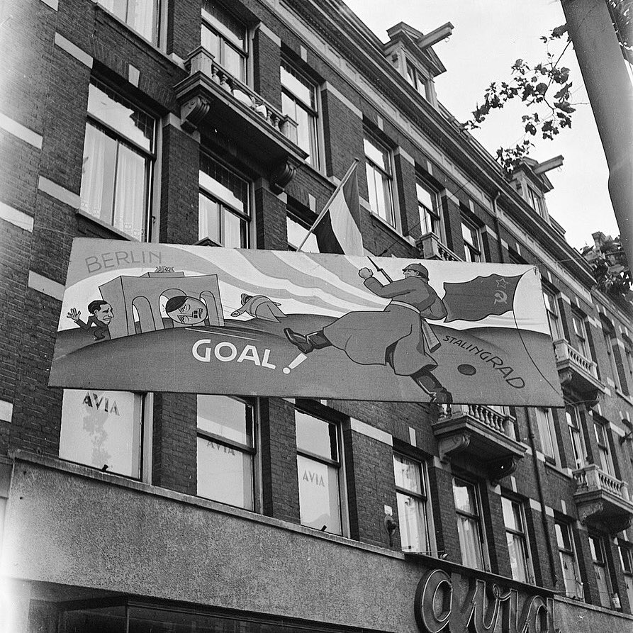 A banner depicting a Soviet soldier shooting Hitler in the head through the Brandenburg Gate, displayed in Amsterdam, Netherlands, June 1945.