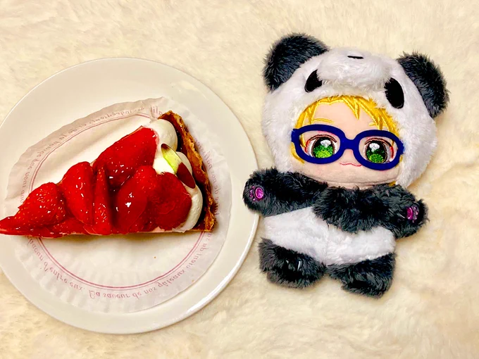 急にパンダ着せられてイマイチ馴染んでないぬいと、周りのごちゃごちゃしたものを避けるために真上から撮られたおたおめケーキ