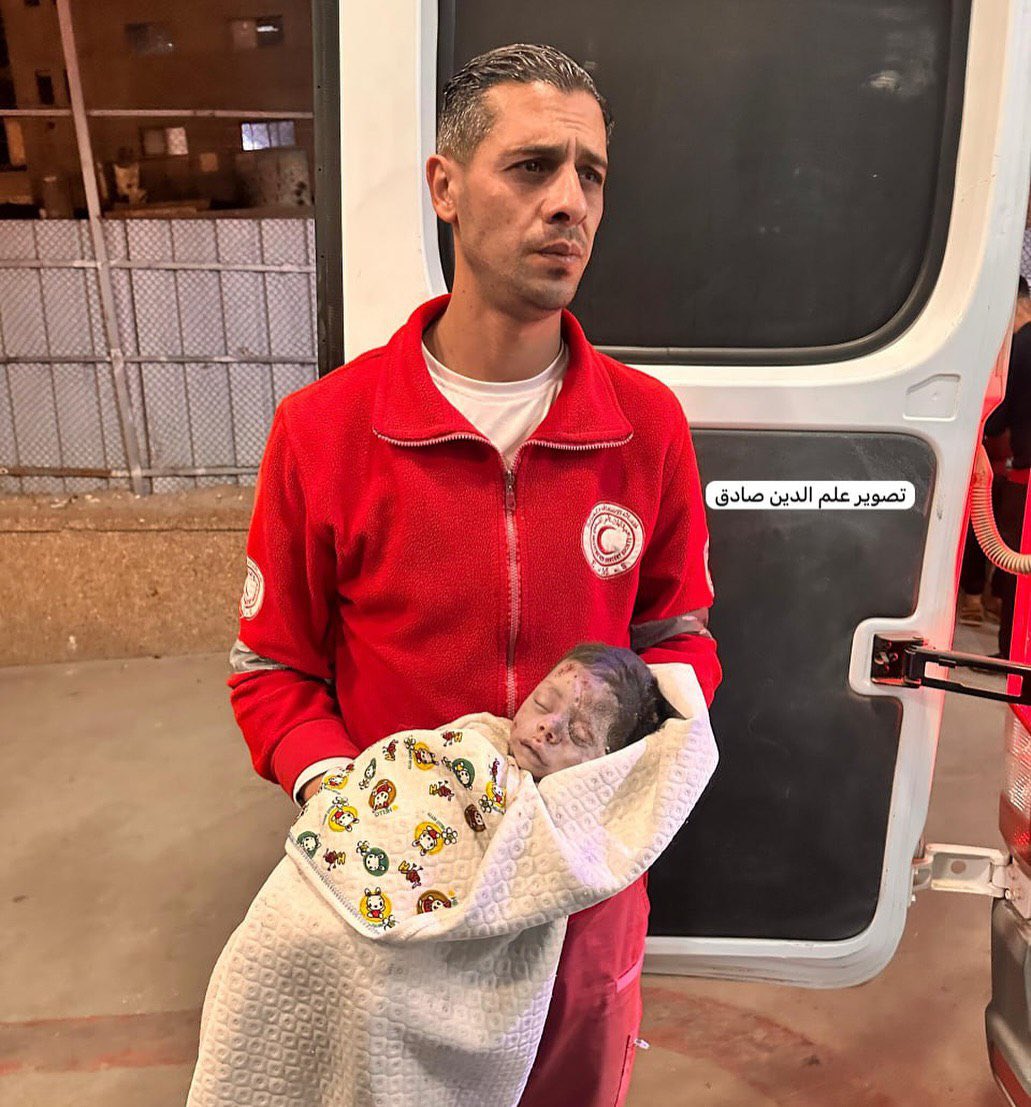A paramedic carries the body of an infant who was killed in the Israeli air strikes in Khan Younis city.