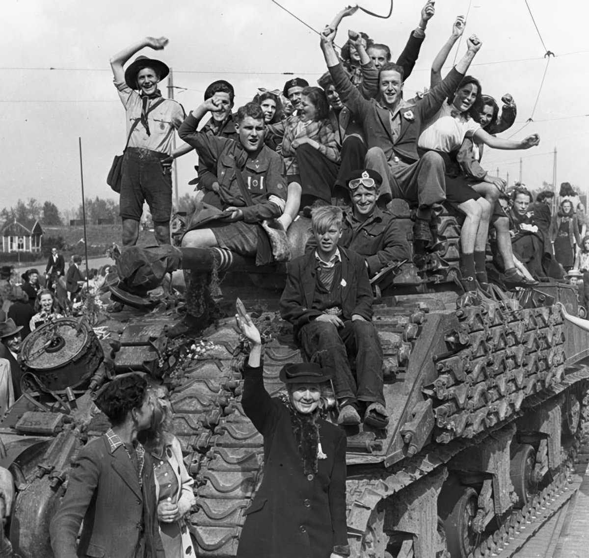 Civilians surrounding a Sherman tank of the 4th Canadian Armoured Division during the liberation of Hilversum, the Netherlands on May 7th, 1945.

Throughout April and May 1945, Canadian and other Allied forces were enthusiastically welcomed by the Dutch people, freed from almost