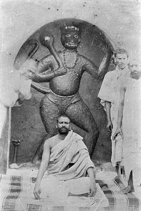 इस तस्वीर में नीम करौली बाबा महाराज जी उनके द्वारा  बनायी गई विशाल हनुमान जी की विधाल प्रतिमा के सामने ध्यान अवस्था में बैठे हुए है।