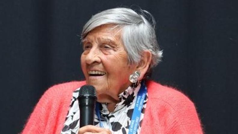 À 100 ans, Ginette Kolinka continue de transmettre la mémoire de la Shoah avec une force bouleversante.
Le 16 avril 2025, cette rescapée des camps de la mort a rencontré des jeunes pris en charge par la protection judiciaire de la jeunesse (PJJ) à la gare de Bobigny – lieu