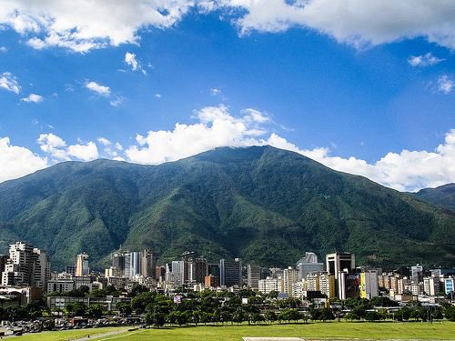 TifuchoII's tweet photo. Donde el silencio también habla en español 

Y si muero, que sea en Venezuela

Me fui con una promesa que me hice a mi misma la de volver a nacer.
Cruzando cielos ajenos,
pisando tierras prestadas,
arrastrando un corazón que aún hablaba en español.

Allá dejé mis gatos como guardianes de la memoria,
mi casa como un castillo de techos humildes,
mis amigos de cafés largos y silencios compartidos,
mi lengua, la única que sabe decir mamá sin quebrarse.

Aquí,
el pan abunda, se compra,
pero no se comparte.
El sol calienta,
pero no abraza.
La familia se nombra,
pero no llega.

Y yo,
desnuda de todo lo que me hacía ser,
camino entre días idénticos
como quien espera que alguien se siente un rato a conversar.

He perdido las alajas que colgaban de mi corazón,
la olla que hervía como tambor de fiesta,
las manos que sabían escribir,
las especies que ponía a cantar.
He extraviado incluso la voz con que solía rezar.

Y en medio del intento de renacer,
la vida me ha dado sepultura.

Hoy no quiero más que dormirme sin ruido,
como se duerme la sabana cuando nadie la mira.

Pero si cierro los ojos del alma —si me rindo del todo—
que no sea lejos de mi tierra.
Que me aniden bajo la sombra del Ávila,
donde la lluvia cae con sabor a mango y a semeruco.
Que mi tristeza se disuelva en el Orinoco,
que mis despojos sirvan de alimento a las raíces de un araguaney.
Pero que no me lloren las madres que ya han llorado mil veces.
Que me abrace el lamento de un turpial.
Que me recen las mujeres que rezan sin fe.

Porque solo allá,
en la soledad infinita de mi Venezuela,
el dolor es idioma,
y el silencio,
poesía.

M. Orta