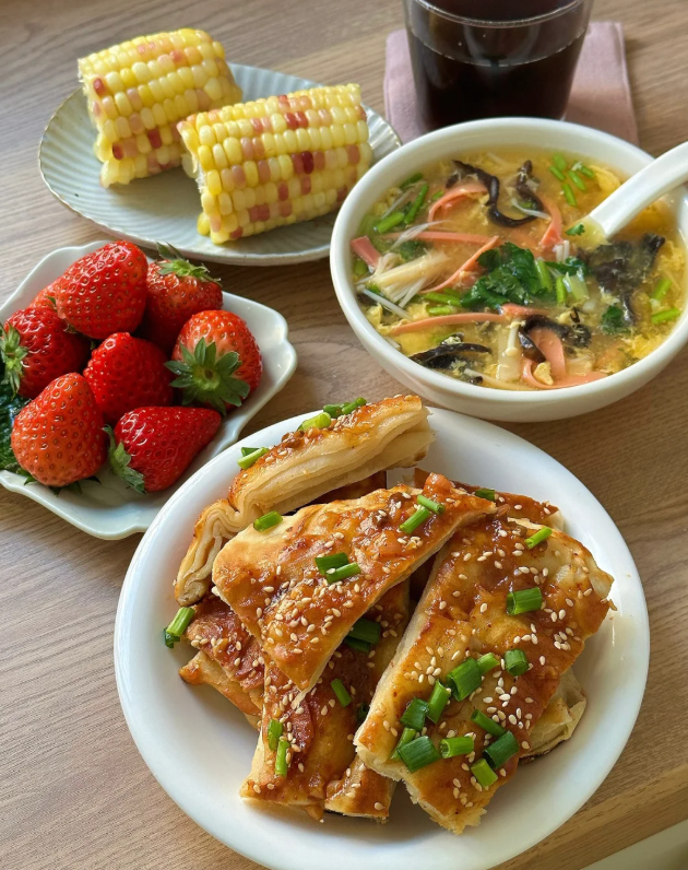 おはよう！今日の朝ごはんはとっても豪華🍴✨
👉 サクサク香ばしいごまネギ卵焼きに、熱々の野菜スープを添えて🥣
👉 さらに甘くてジューシーなイチゴ🍓とカラフルなトウモロコシ🌽も一緒に♪