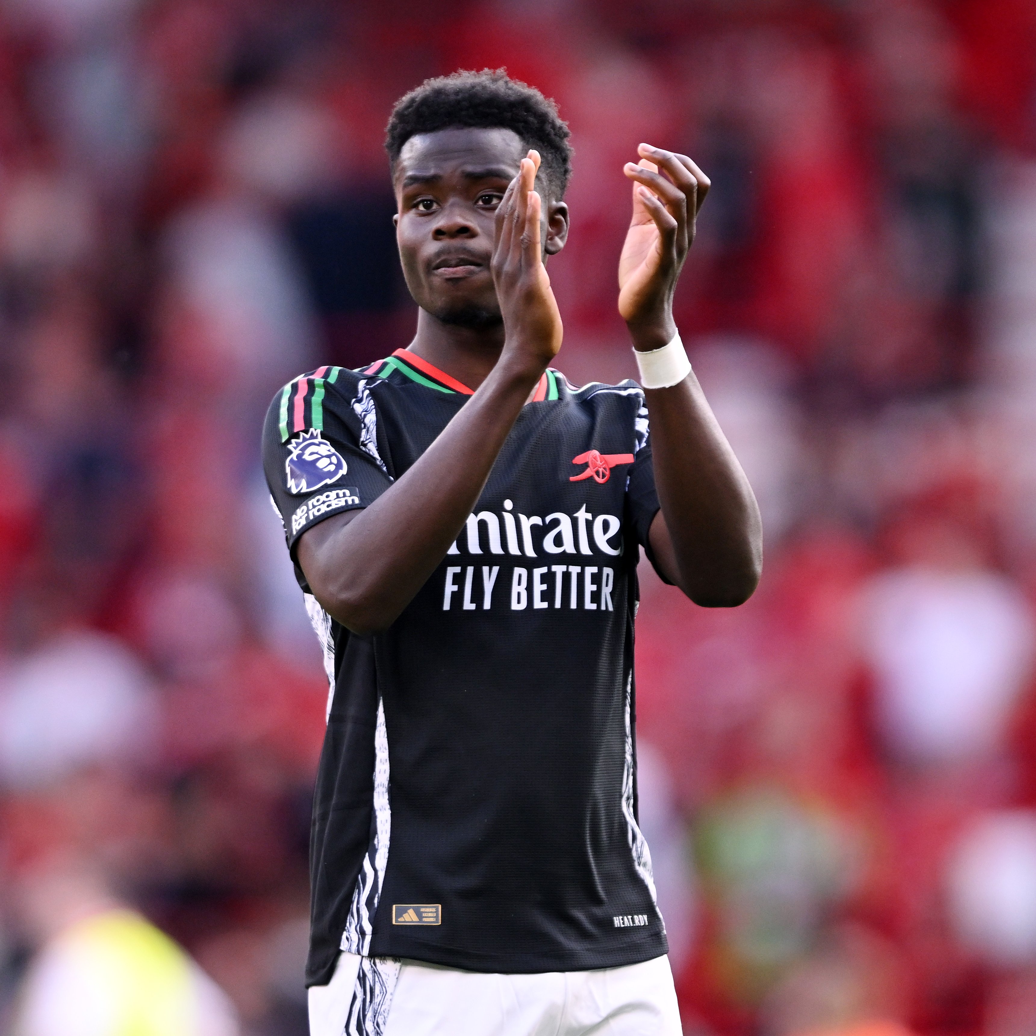 Bukayo Saka applauds the away faithful.