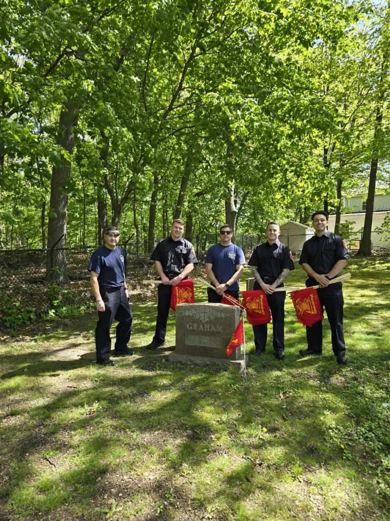 Captain Jim Marshall, assisted by firefighters, placed flags at the graves sites of firefighters buried at cemeteries in town. Captain Marshall is shown at the burial site of his father, FF John Marsahall. The Firefighters are at the grave site of Captain John "Jack" Graham.
