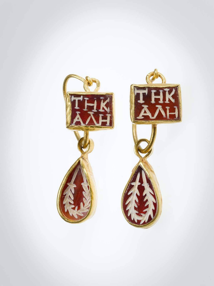 These earrings, inscribed with the Greek phrase "ΤΗ ΚΑΛΗ" (ti kale), meaning "to the beautiful one," date to approximately the 4th century AD, from the Imperial Roman period. Crafted from gold and adorned with finely carved sardonyx. Collection: Museum of Fine Arts Boston
