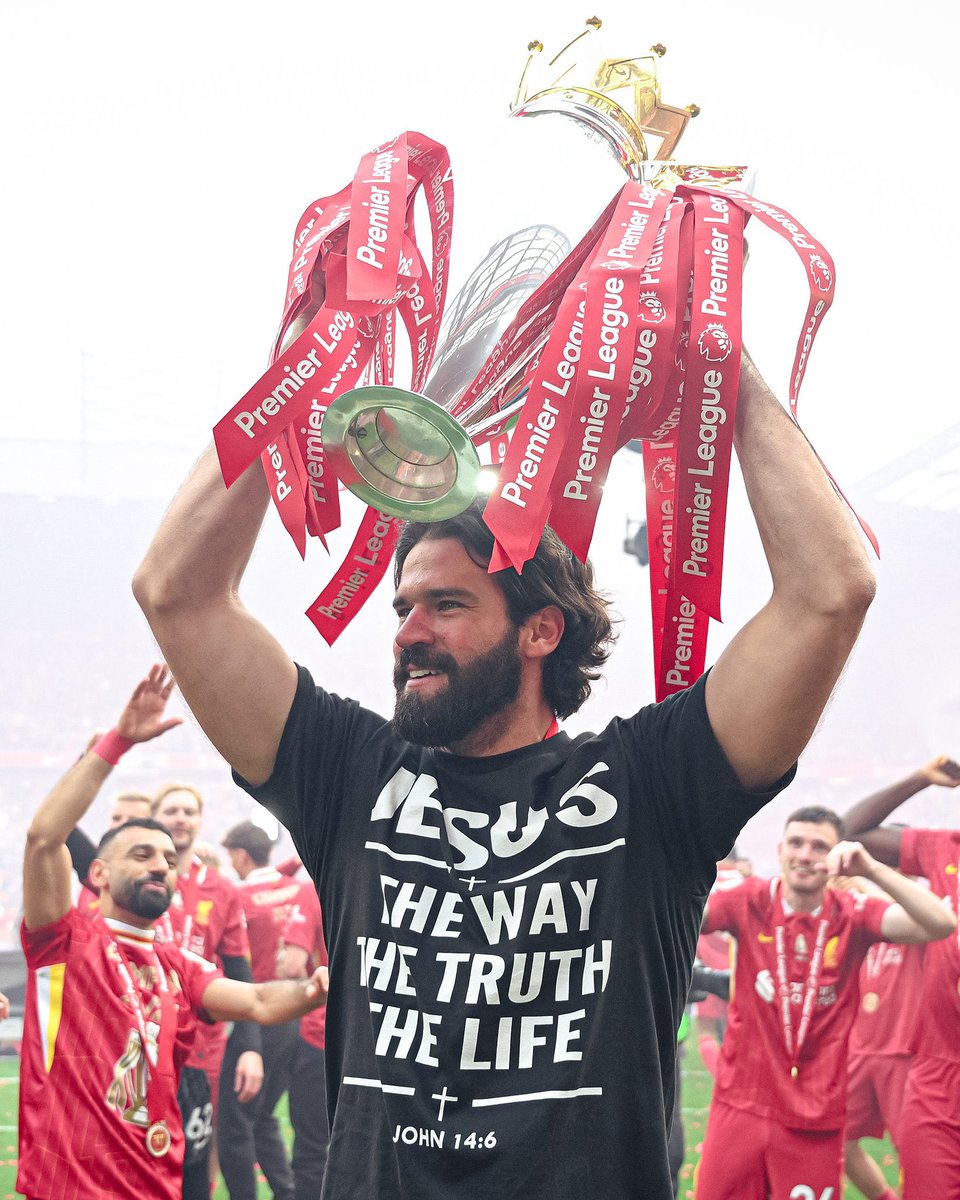 Liverpool FC's Alisson Becker lifting the Premier League trophy and wearing a shirt that reads "Jesus is the Way, the Truth, and the Life" ✝️
