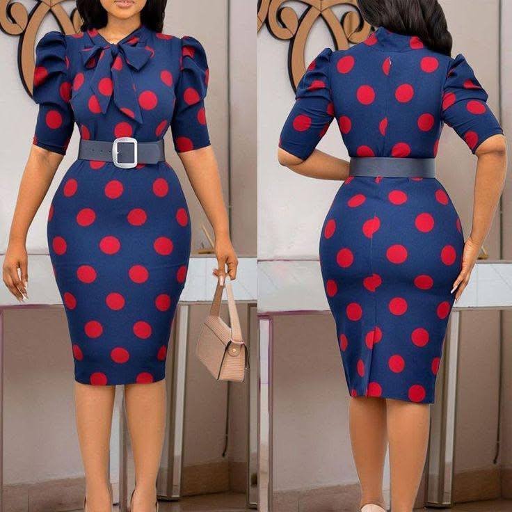 shirojinsei1's tweet image. A woman models a form-fitting navy dress with red polka dots, featuring puffed sleeves, a large bow at the neck, and a belted waist, shown from both front and back views. She accessorizes with a beige handbag and nude heels.