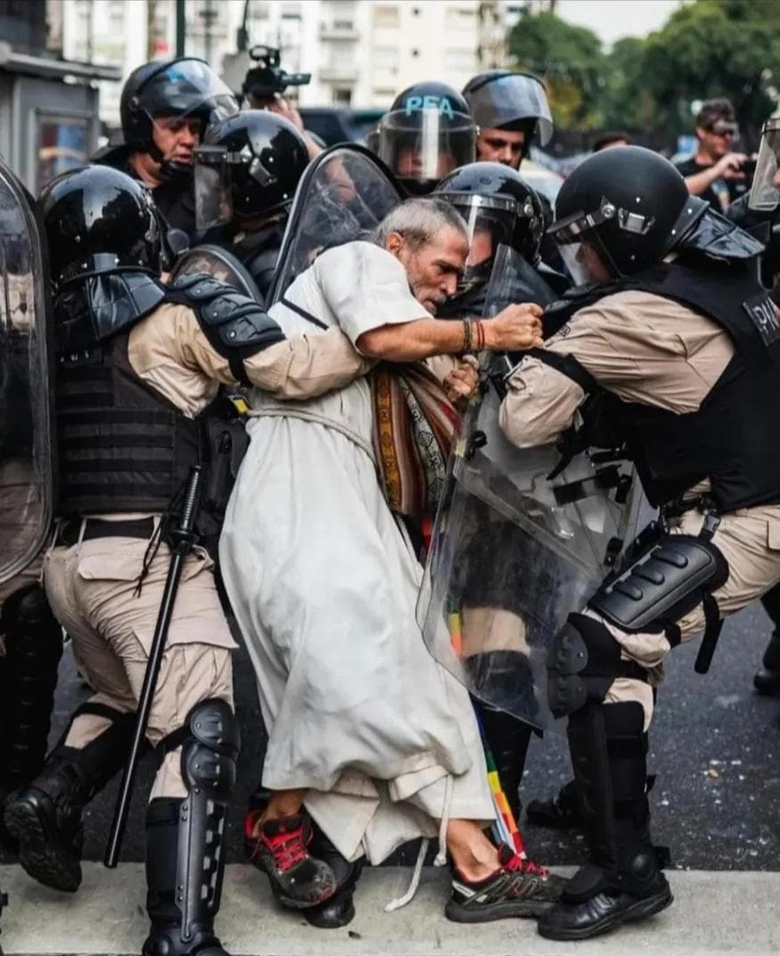 Imagen que debe de recorrer el mundo.
14 de Mayo del 2025,represión contra los jubilados y acompañantesba. 
Un sacerdote,misionero, comprometido con la paz, cómo Jesús de Nazareth, golpeado por varios miembros de la PFA - Policía Federal Argentina -. 
EL GENOCIDIO ASCENDENTE !!!