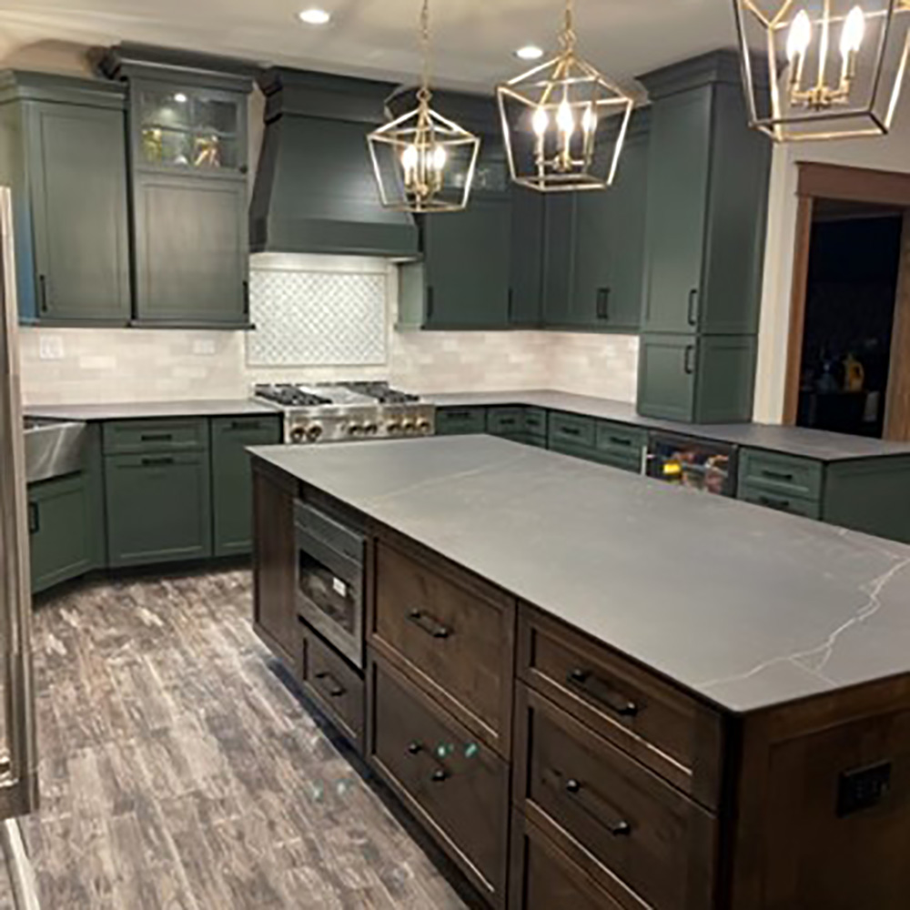 This forest-inspired kitchen is dark and moody. Bringing in color drenched cabinetry in deep green rich-dark wood stain. This kitchen was designed by Home Depot designer Maria D’Amore.