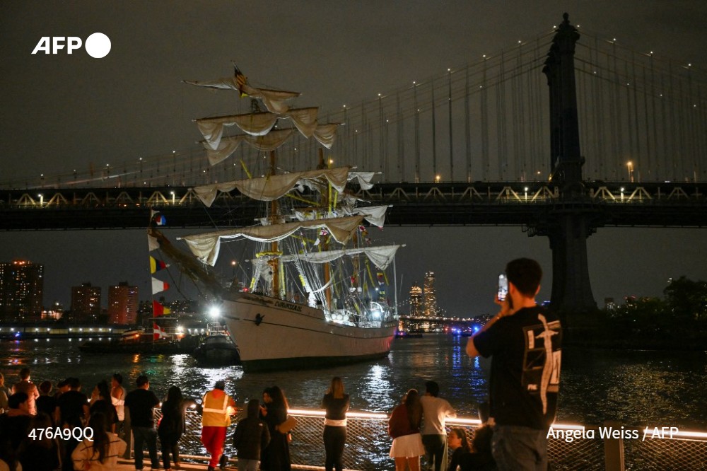 Onlookers watch as a Mexican Navy training ship is pulled away after it slammed into the nearby Brooklyn Bridge in New York on May 17, 2025