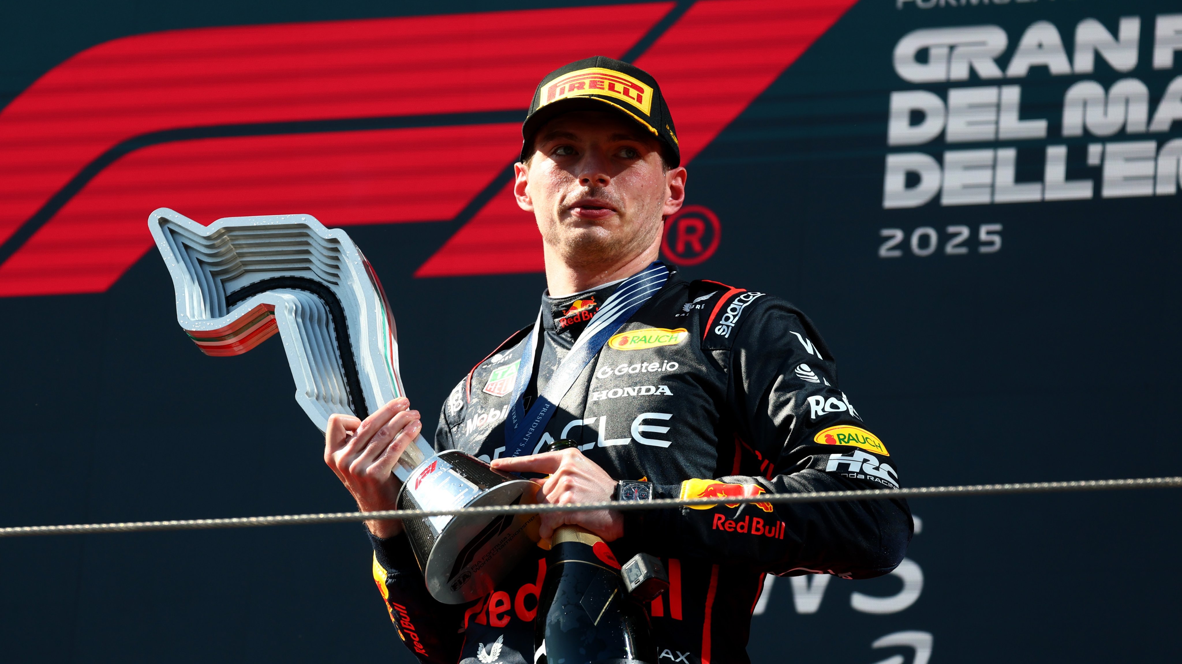 Max, soaked in champagne, holds his winner's trophy.