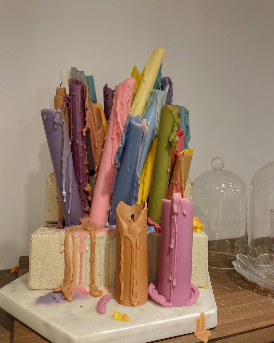 nancyjo1070's tweet image. A vibrant, dripping candle sculpture on a marble base, showcasing a chaotic blend of colors. #ArtInstallation #CandleArt #Sculpture