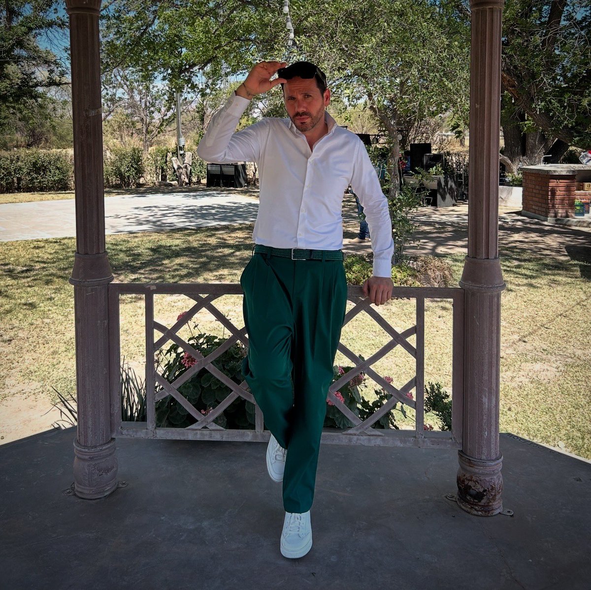 Sol, lente oscuro y pantalón verde.