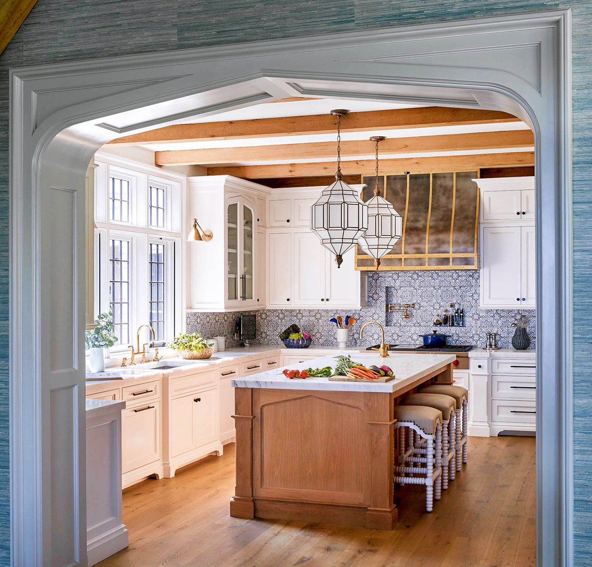 Rustic meets refined in this custom kitchen. Highlights include its natural wood island and beamwork, stained character-grade hardwood floors, painted cabinetry and a metal range hood. #beautifulhomes #homedesign