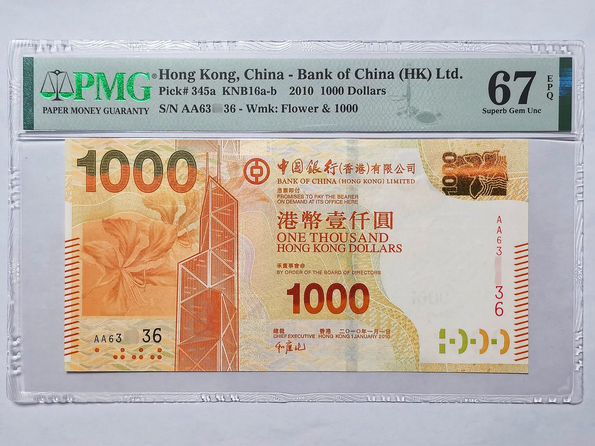 香港2010年中国银行版1000 元纸币，正面图案均为香港中银大厦和紫荆花，背面为太平山俯瞰维多利亚港。系列首次使用初代SPARK光彩光变技术和变色开窗式安全线，防伪技术再上新 台阶，拍入AA首发冠雷达号的PMG67分评级币。