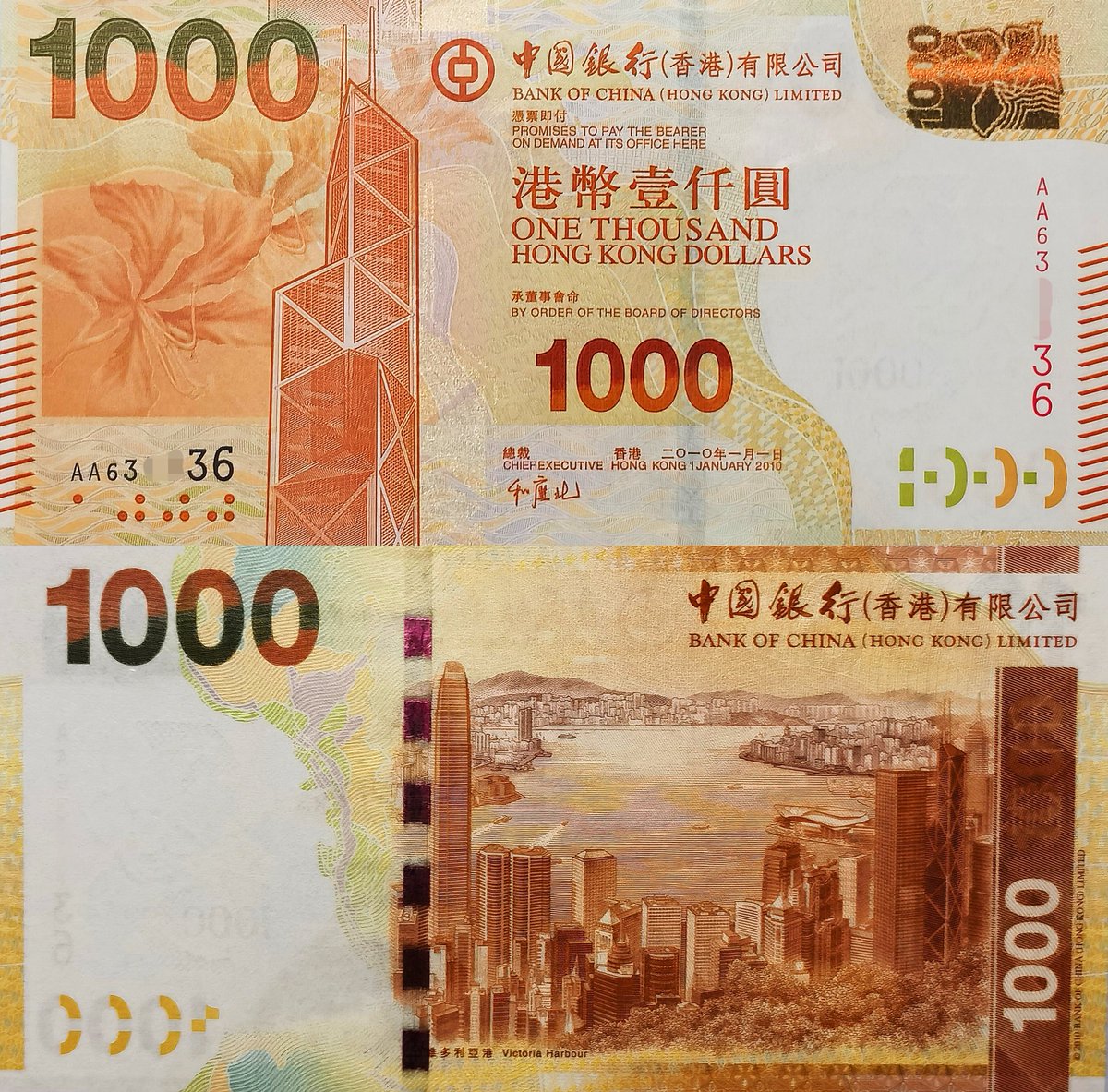 香港2010年中国银行版1000 元纸币，正面图案均为香港中银大厦和紫荆花，背面为太平山俯瞰维多利亚港。系列首次使用初代SPARK光彩光变技术和变色开窗式安全线，防伪技术再上新 台阶，拍入AA首发冠雷达号的PMG67分评级币。