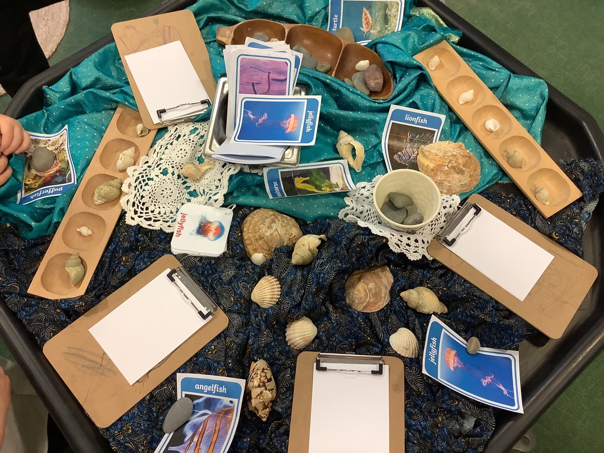 Reception helped to create an ocean tray with natural materials, different textures &amp; photos of sea creatures to explore. With both maths &amp; writing opportunities children are leading their own learning. This group used the clipboards to draw &amp; label things they found on the tray!