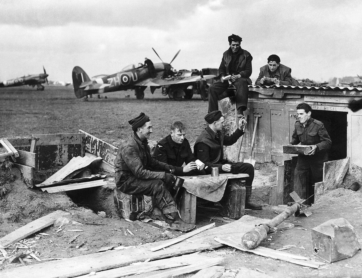 📷 Tea break for an RAF maintenance crew servicing Hawker Typhoon aircraft during WWII. Note the name 'Ritz Hotel' above the door of their hut.

© Mirrorpix