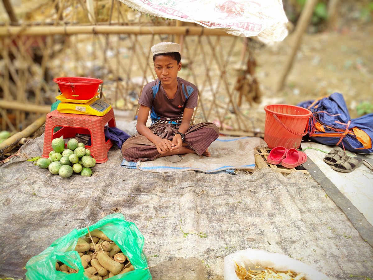 RoAnisHlaMyint's tweet photo. A young Rohingya refugee boy sells vegetables and dried fish 🐟 by the road. He works hard to help his family, pay for school, and save for his future.  

His small stall is full of hope. Every sale is a step toward a better life.

#HopeForRohingya #EducationIsPower https://t.co/qsysYuIXTB