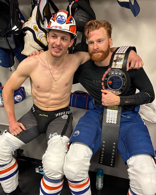 Troy Stecher wears the hard hat and Connor Brown poses with the championship belt for a post-game photo in the Oilers locker room