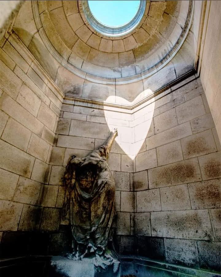 redhistoria's tweet photo. Escondido en el histórico Cementerio de Laeken, en Bruselas, se encuentra un mausoleo que atrae la atención una vez al año por su impresionante exhibición. Construido en 1920 para Léonce Evrard y su esposa, Louise Flignot, la tumba presenta una solemne escultura de un doliente con el brazo extendido hacia una pared vacía. Sin embargo, es en el solsticio de verano, cuando el sol alcanza su punto más alto, cuando se revela la verdadera magia del mausoleo.

Justo al mediodía del 21 de junio, la luz del sol se filtra a través de una abertura en el techo, creando un haz de luz en forma de corazón. Este resplandor etéreo se forma durante unos instantes, flotando sobre la mano del doliente, casi como si la figura extendiera la mano hacia este simbólico corazón de luz.

El fenómeno dura solo unos 15 minutos, pero ha cautivado a los visitantes durante décadas, muchos de los cuales lo ven como un romántico testimonio de amor eterno. El corazón de luz, proyectado durante el día más largo del año, añade una profundidad emocional a una escena que de otro modo sería sombría.