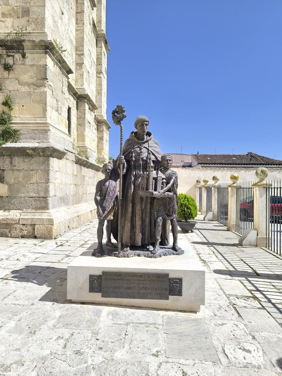 Escultura del Cardenal Cisneros en la lonja de la Catedral Magistral de Alcalá de Henares.
Lleva el hábito franciscano, calzado con sandalias, revestido con la muceta y el capelo cardenalicios, portando báculo y acompañado de las figuras de los Santos Justo, que porta las dos