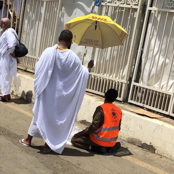 A pilgrim uses an umbrella ☂️ to shade a member of the #Hajj security team 👮‍♂️ as he prays 🙏🕋.