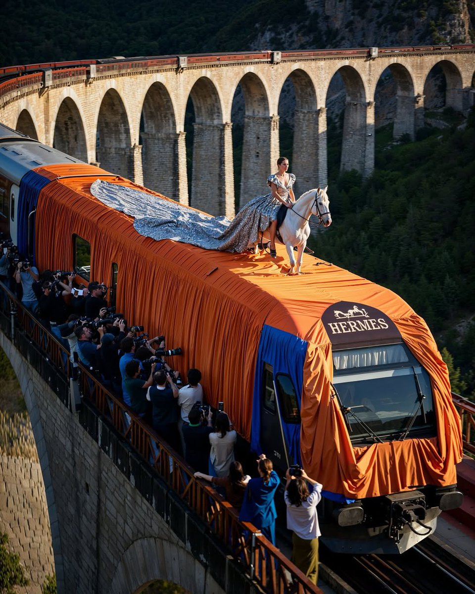 lofficielhk's tweet image. #LOFFICIELfashion：AI 再次發揮創意，打造品牌的奇幻延伸台？繼早前 AI 藝術家 If Only 讓 Chanel、Louis Vuitton、Versace 等品牌在天空中走騷之後，這次更將時裝騷搬到火車車頂。每輛列車都換上專屬品牌的標誌與設計元素，成為流動舞台。你又會期待這樣的畫面成真嗎？
#AIGenerate #LuxuryBrands