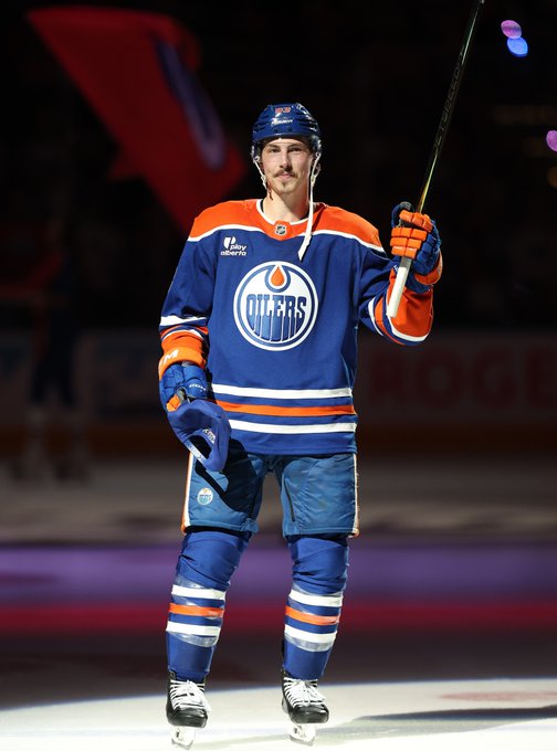 Ryan Nugent-Hopkins saluting the crowd on ice in an Oilers uniform.