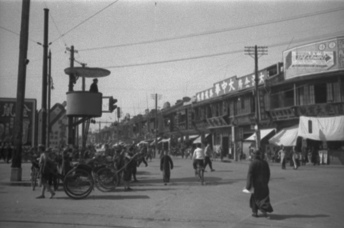 A street scene in Shanghai, China captured by photographer Harrison Forman in 1937. We can see billboards to the left and a large advertisement for Wrigley's chewing gum on the building to the right.