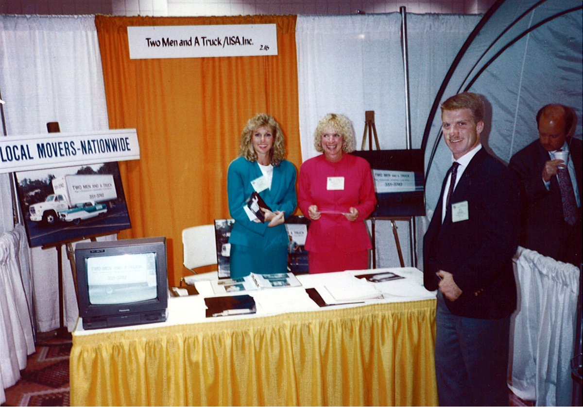 Here's a throwback photo featuring members of the TWO MEN AND A TRUCK founding family - Mary Ellen Sheets, Jon Sorber, and Melanie Bergeron - at a trade show in the late 1980s. #ThrowbackThursday