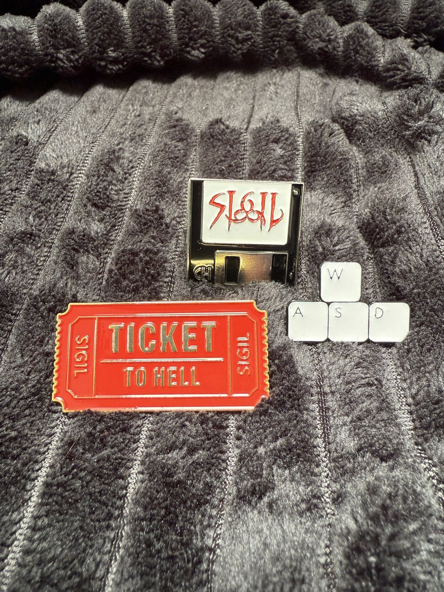 romero's tweet image. Ships next week! The original SIGIL in a new embossed foil box w/real 5.25" and 3.5" disks. Runs on classic machines & you get a digital download! New merch includes three pins, a foil sticker sheet, cover art poster and cinch bag. While supplies last. Romero.com.