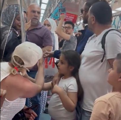 kozluklufuat's tweet photo. Vicdani borcum olarak dün öğleden sonra Marmaray’da seyahat ederken önümde yaşanan ve yumruklu kavgaya dönüşen olaya dair birebir tanıklığımı aktarmak isterim. Konunun bu denli lince varacağını düşünmemiştim. 

Mesele görüntülerde izlenenden ibaret değildir, kavgaya dönüşme aşamasında bir gazeteci refleksiyle video kaydına başladım. Öncesinde olanları anlatmak gerekiyor.
 
İki çocuğuyla Marmaray vagonuna sanırım Erenköy ya da Bostancı’dan binen beyefendi, kapının kenarında duran ve telefonla konuşan genç hanımefendiye, “niye burada duruyorsun, çocuklarımla girmeye çalışıyorum, zorlandılar. Ya ayakları takılıp sıkışıp düşselerdi” diyerek çıkıştı.
 
Genç kız “affedersiniz” karşılığını verdi, özür diledi. Oysa vagona biniş kapısının ortasından rahatlıkla girilebiliyordu. Vagon içi güvenlik kameraları kaydetmiştir diye düşünüyorum. Sürekli toplu taşımayla seyahat ettiğim için çok sık görüyorum, kapının sağında solunda her zaman birileri duruyor maalesef. Kimisi bir iki durak sonra ineceği için vagonun iç kesimlerine ilerlemiyor. Kimiz de kalabalığa karışmak istemiyor. Ya da yol boyunca dışarıyı görüntülüyor, fotoğraf çekiyor. Ancak bu acı olayın yaşandığı sırada çocuklu beyefendinin geçişini zora sokan bir kalabalık yoktu.
Burnu kırılan beyefendi vagona bindikten ve kapılar kapandıktan sonra söylenmeye devam etti. Dakikalarca sürdü bu durum. Sanırım 5-6 dakika… Kapıda duran hanımefendi de ağlamaya başladı. Bunu gören yolcular adama “yeter yahu susun, kapatın konuyu” diye uyarıda bulundu. Ne yazık ki çocuklarının elini tutan adam susmadı, söylenmeye devam etti. Olayın müştekisi durumuna düşen iki kişi de ağlayan genç kızın durumundan hareketle “yeter artık ulan, ne bu kadar büyüttün be” gibi sözlerle adama doğru yürüdü. Ben de cep telefonumun kamerasını açıp kayda başladım. Tutuklanan kişi, çocuklu babaya Marmaray durağa yaklaştığı sırada “çık dışarı” dedi ve yumruk atıp vagondan indi. Marmaray hareket etti. 
 
Diğer genç de söylenerek burnu kırılan adama yanaştı ve onu ittirdi. Taraflar Süreyya Plajı durağında indi. Adamın burnundan oluk oluk kan geliyordu. Herkes şoke olmuştu. Marmaray özel güvenlik elemanları koştu geldi. Burnu kırılan adam kendisine sözlü ve fiziki müdahalede bulunan mavi gömlekli gençten şikâyetçi olduğunu bağırdı. Sonra da kız arkadaşıyla konuşarak uzaklaşan gencin arkasından koşup yumruk attı. Sonrasında Marmaray hareket etti. Tanıklığım bundan ibaret.
 
Temennim, iki tarafın da öfkelerine yenik düşüp hatalar yaptığı bu tatsız hadisenin farklı boyutlara tırmanmadan kapanmasıdır. Her gün toplu taşıma araçlarında seyahat ettiğim için söylemeliyim ki öfke kontrolünde sıkıntılarımız var. @TC_istanbul @istanbul_EGM