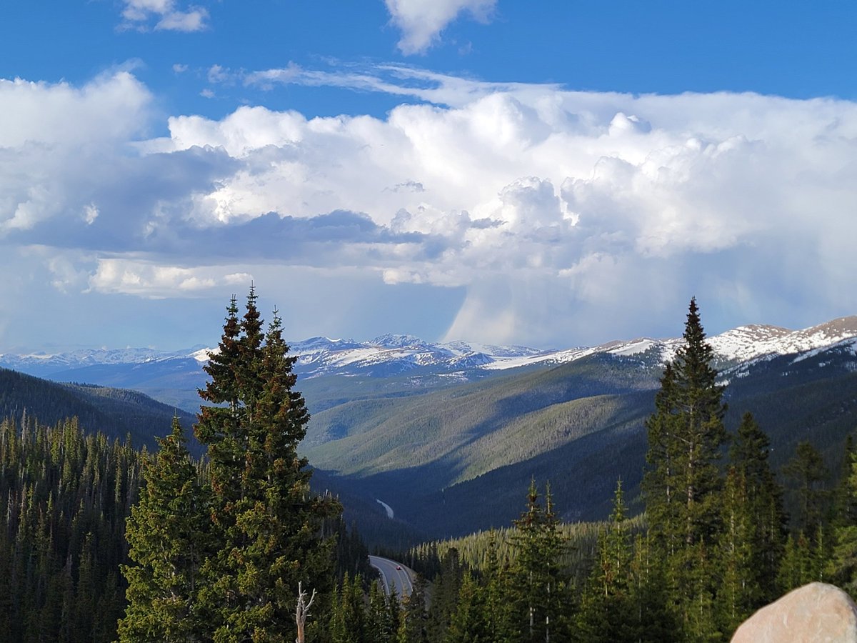On a high peak right now where the snow capped peaks are present and rain showers can be seen in the distance