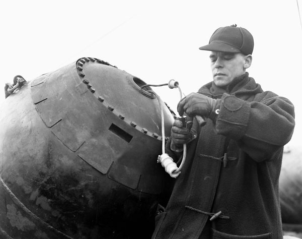 Unidentified rating adjusting the electrical wiring of a mine aboard the minelaying vessel HMCS SANKATY, Halifax, Nova Scotia, March 1941. (LAC a105210-v6.jpg) #Archives #RCN