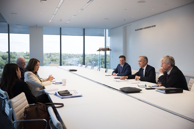 Prime Minister Mark Carney sits at a table across from Premier Danielle Smith during a meeting in Calgary, Alberta.