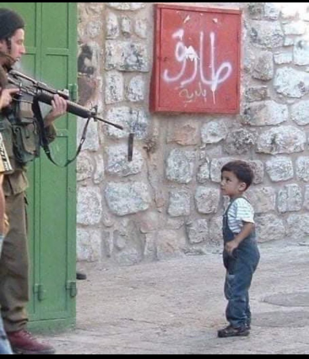 Once again I present to you a rare moment captured in time. 

Even through a child's eyes and with a child's mind, this little boy recognizes his oppressor, his occupier. 

The Israeli soldier sees differently as he points his rifle at the small and unarmed child's. He sees an