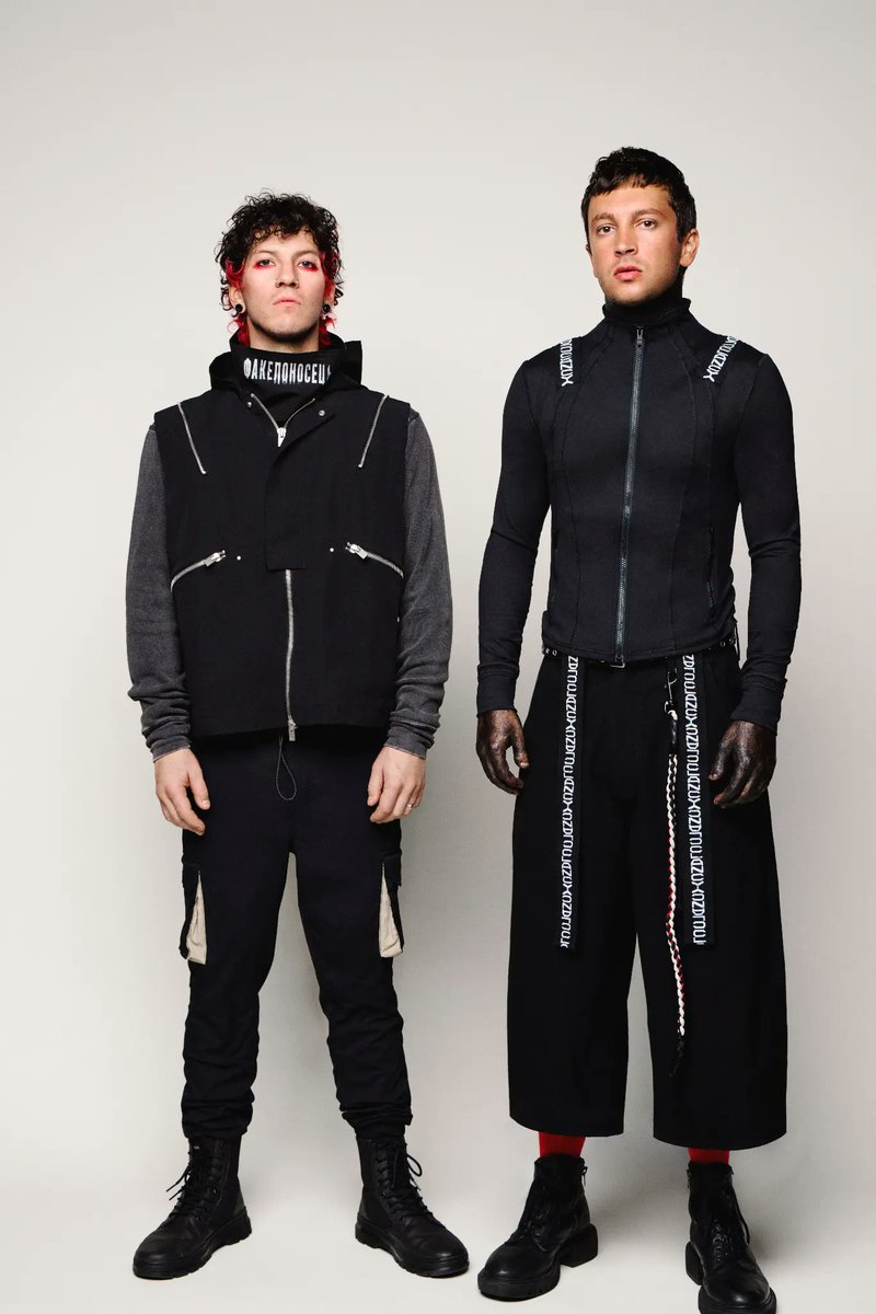 icharnou's tweet photo. In the promo photo for Breach, Josh has 'факелоносець' on his neck, and Tyler's 'Clancy' tape forms a | / shape. If you put Josh's line between Tyler's shoulders, it creates the band's logo |-/! https://t.co/ODvVG7p91J