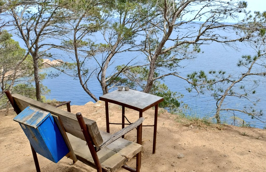 Banc, taula i bústia amb un llibre de piades per dir-hi la teva en un balcó de l'Empordà.