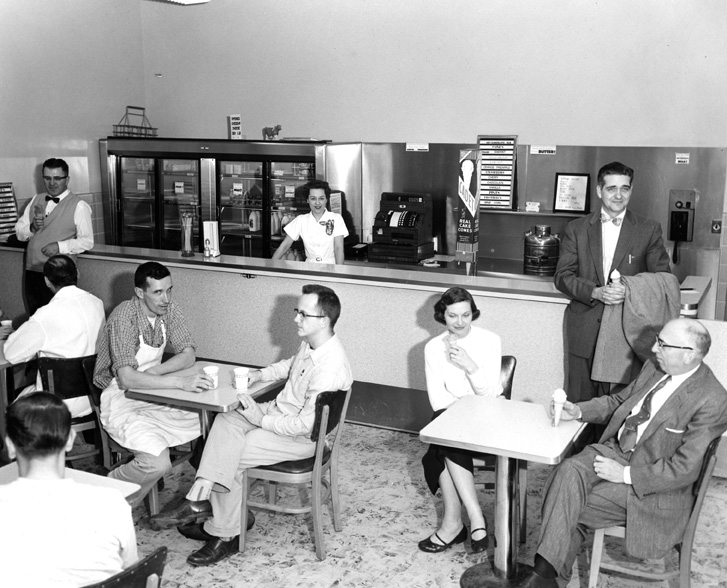 #DYK that the Dairy Store has been a bustling spot on campus for decades? This photograph taken on March 14, 1957 shows an employee behind the counter and people sitting at tables enjoying ice cream. #MSUHistory