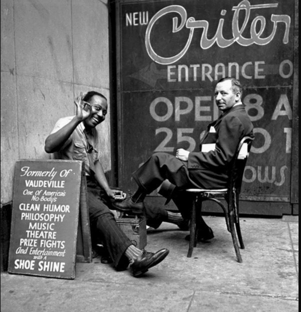 A shoe shiner, offering clean humor, philosophy, music, etc., all for the price of a shoe shine.

1947 photo by Fred Stein.