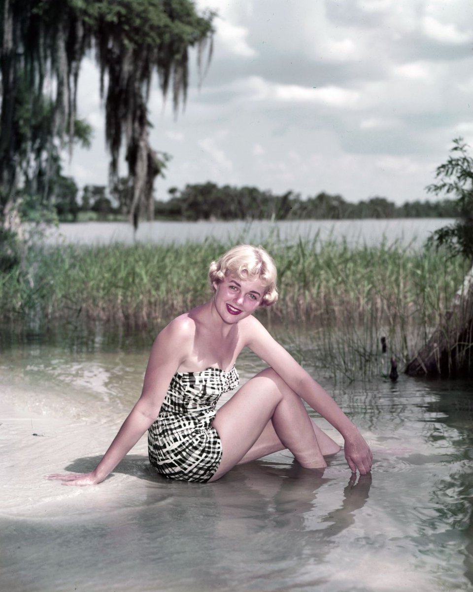 Lake Eloise, 1954: Linda Leader of Ohio poses at the water’s edge near Cypress Gardens in Polk County, Florida. Spanish moss-draped Bald Cypress trees and aquatic grasses line the natural lake.