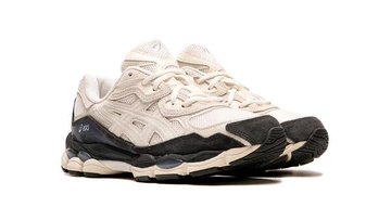 The image showcases a pair of ASICS GEL-NYC sneakers in a "White/Smoke Grey" colorway, as indicated by the post text. The sneakers are displayed from multiple angles, highlighting their design and color scheme. The shoes feature a combination of white mesh and leather with dark grey accents, particularly on the sole and heel. They are placed on top of a brown box with a minimalist design, which complements the aesthetic of the sneakers. The post text mentions the release date as June 15, 2025, and provides a link for more information, suggesting that this is a promotional post for the upcoming release of this specific model.