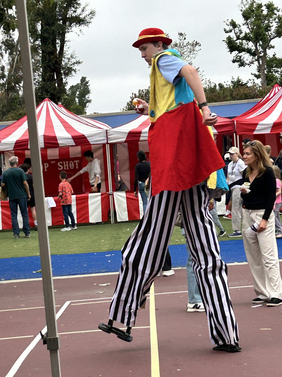 Man on stilts at our school carnival is trying to kick up his heels.