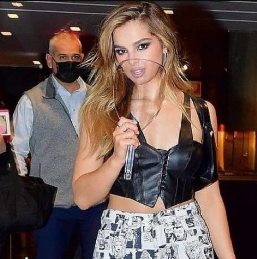 Addison Rae poses with a blown-up version of her 2021 face shield meme.