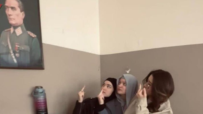 Seferihisar Uluslararası İmam Hatip Lisesi'nde üç yabancı uyruklu öğrenci, Atatürk portresine el hareketi çekerken poz verdi.