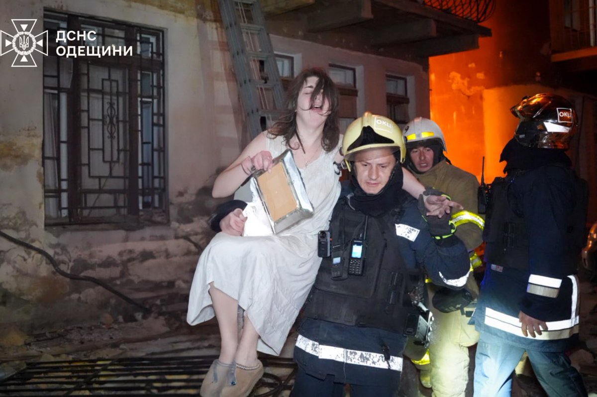 A girl rescued from a fire in Odesa, clutching a framed photo to her chest.